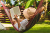 femme avec chapeau de paille dans un hamac lisant un livre