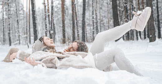 Jeune couple gars fille allongé, jouant dans une forêt hivernale enneigée avec des arbres, marchant, s'amusant, riant dans des vêtements chauds et élégants, concept de temps libre et de passer du temps à l'extérieur.