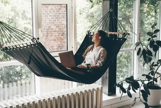 jeune feme dans un hamac simple à barres de bois dans un solarium