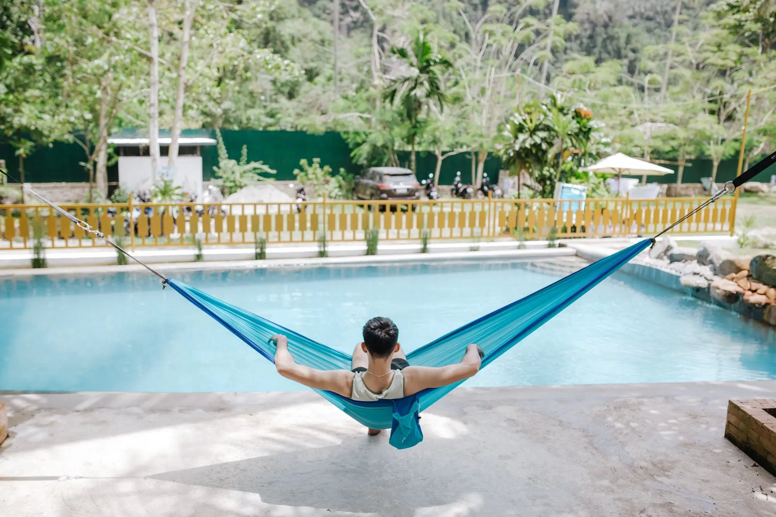 jeune homme dans un hamac au bord de la piscine