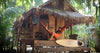 homme dans un hamac orange accroché à une petite cabane dans la jungle