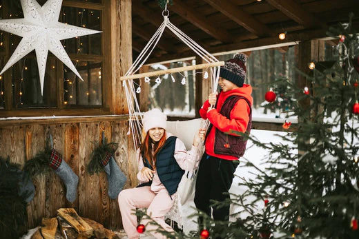 Vacances de Noël enneigées - deux enfants à l'extérieur, dans une chaise hamac, avec un décor de fête