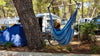 jeune femme dans une chaise hamac bleue sur un terrain de camping